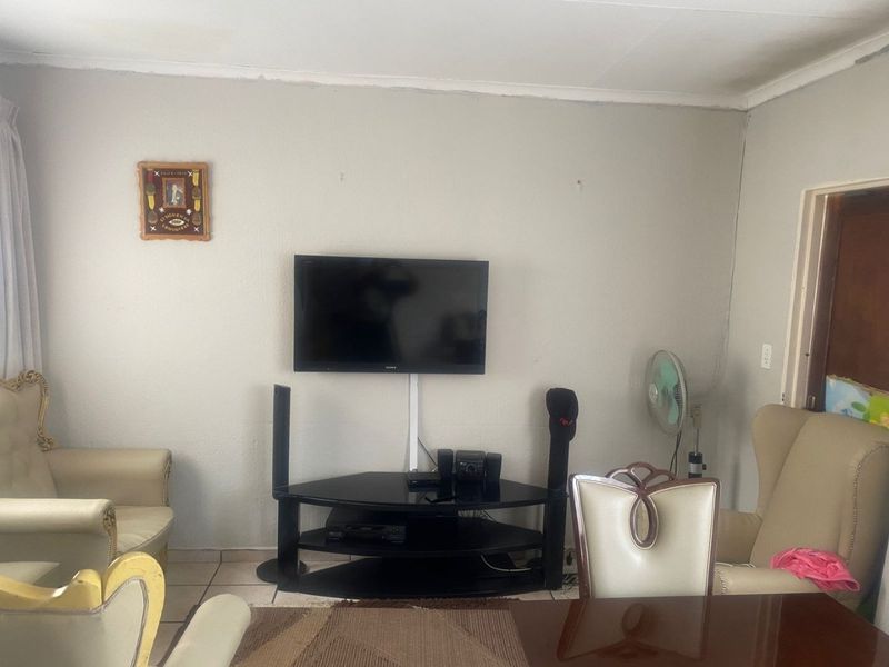 A living room area featuring tiled flooring and coved ceilings, providing a functional space for relaxation and entertainment.