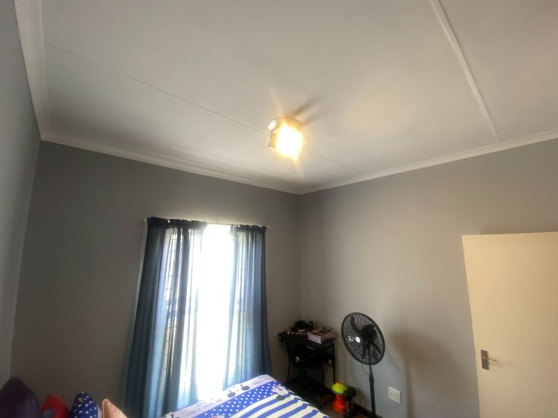 A standard bedroom featuring grey painted walls, coving, and a central ceiling light fixture.