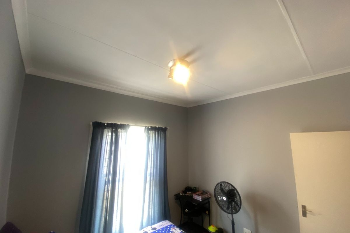 A standard bedroom featuring grey painted walls, coving, and a central ceiling light fixture.
