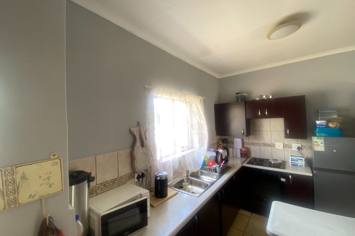 A functional kitchen featuring dark cabinetry, a double bowl sink, tiled backsplash, and built-in cooking appliances.