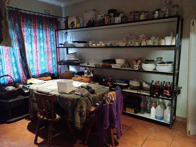 Dining area featuring terracotta floor tiles and a large built-in metal shelving unit for storage.