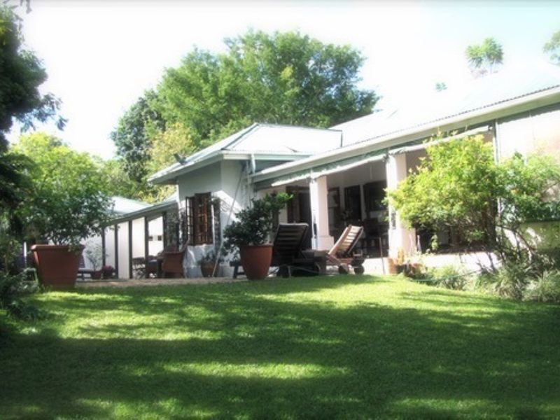A view of the rear exterior of the house featuring a covered patio area overlooking a lush, well-maintained garden.