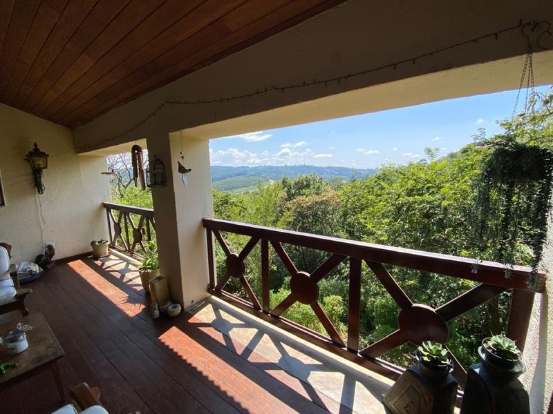 A covered timber balcony featuring a wooden balustrade and ceiling, offering expansive views over the surrounding lush landscape.