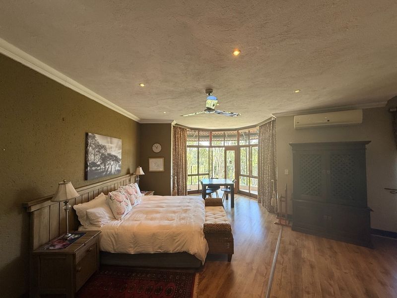 Spacious bedroom featuring laminate flooring, recessed lighting, a ceiling fan, air conditioning, and large bay windows providing natural light and outdoor views.