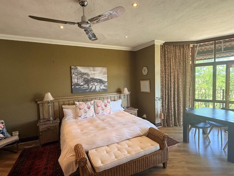 Spacious bedroom featuring laminate flooring, recessed lighting, a ceiling fan, and large windows with access to an outdoor balcony area.