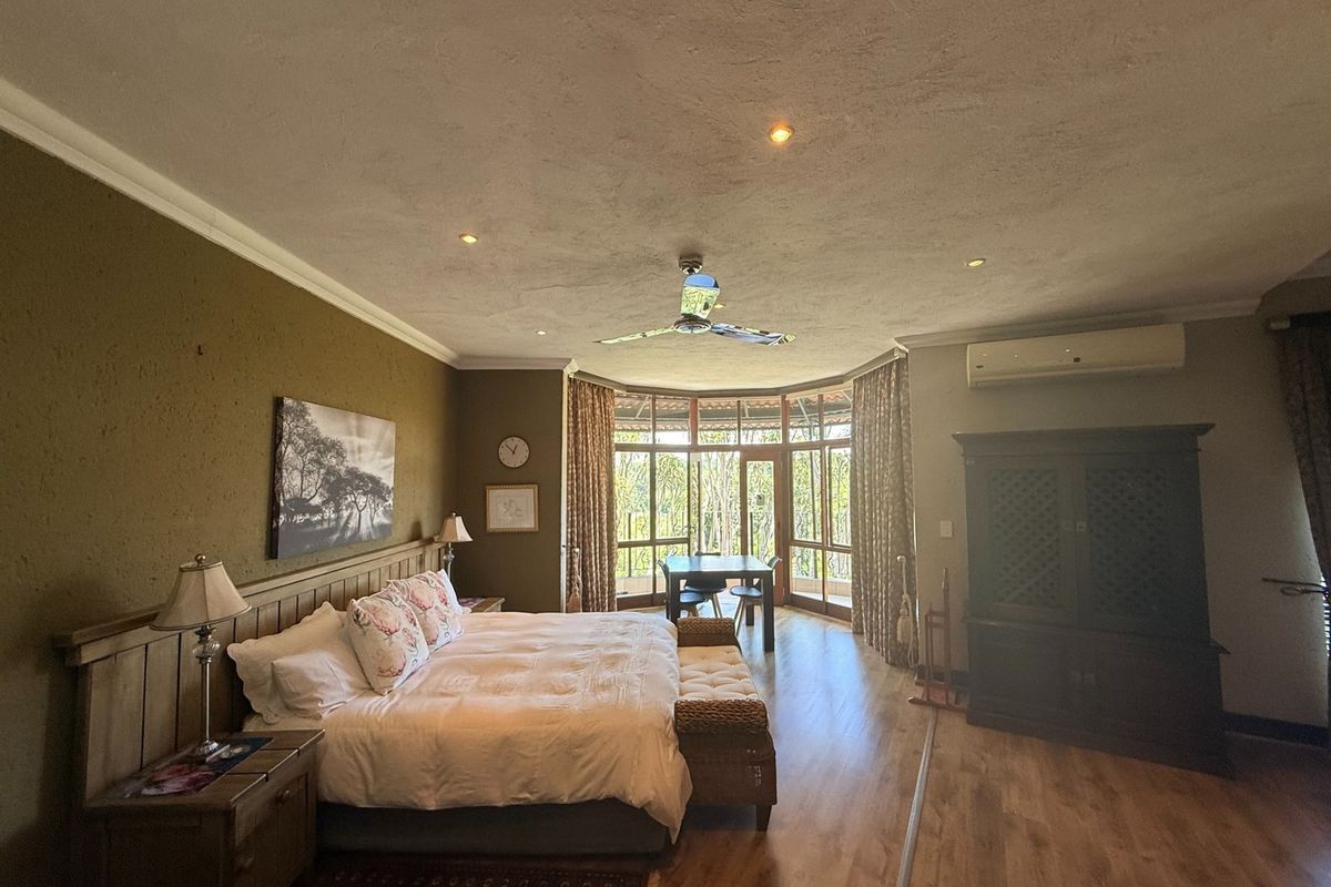 Spacious bedroom featuring laminate flooring, recessed lighting, a ceiling fan, split-system air conditioning, and large timber-framed windows with garden views.