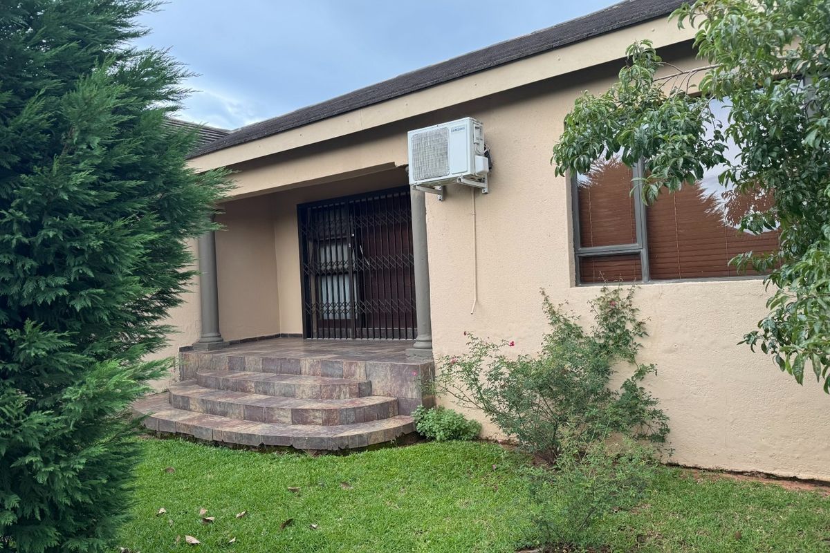 Rear exterior view featuring a tiled patio entrance with security gate, mounted air conditioning unit, and established garden surroundings.