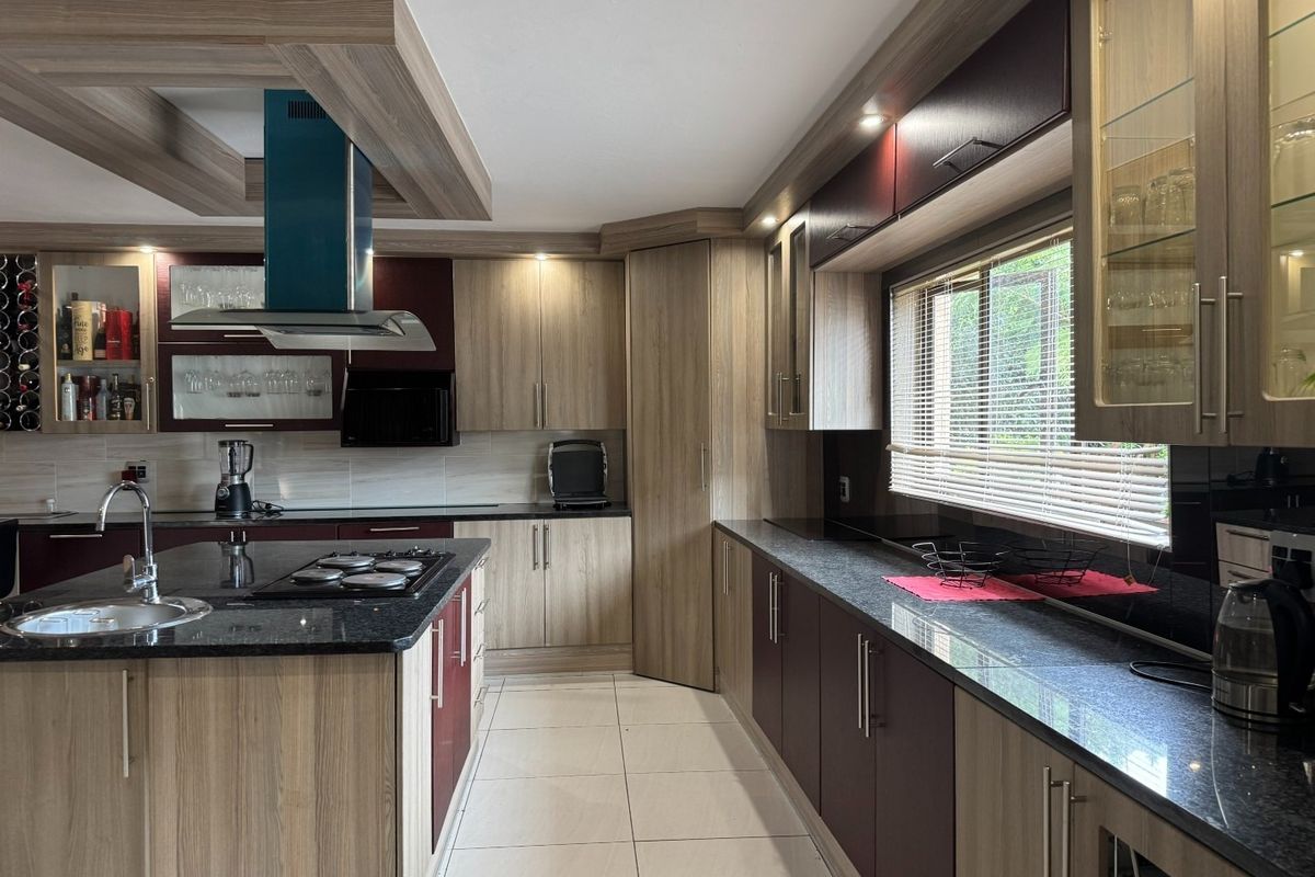 Modern kitchen featuring granite countertops, a central island with a gas hob, integrated cabinetry, and a stylish extractor fan.