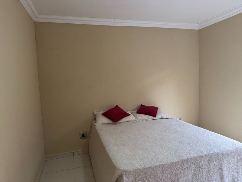 A simple bedroom featuring tiled flooring and crown molding, currently requiring minor cosmetic updates to the wall finishes.