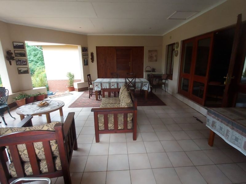 A spacious covered patio area featuring tiled flooring and timber-framed glass doors, providing a seamless transition to the outdoor garden space.