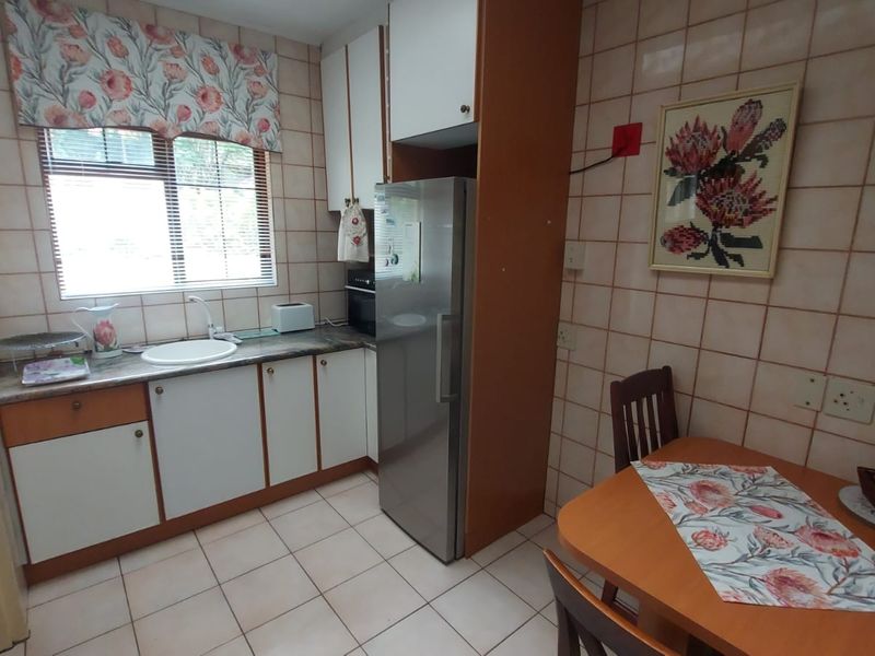 A functional kitchen featuring built-in cabinetry, laminate countertops, and ceramic tiling throughout, offering a practical layout for daily meal preparation.