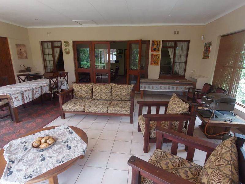 Spacious living area featuring tiled flooring, large windows, and wooden door frames, providing a bright and open space for relaxation and dining.