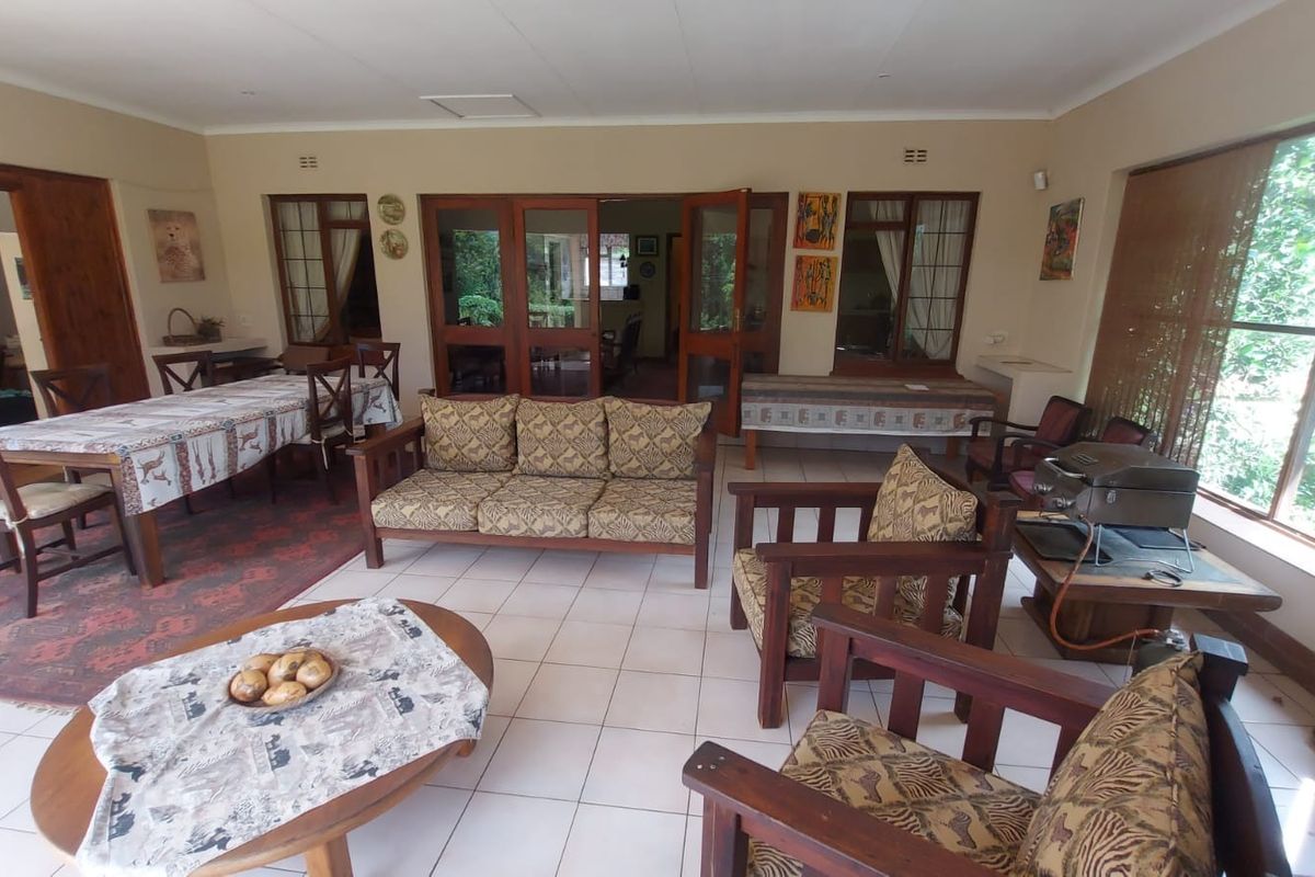 Spacious living area featuring tiled flooring, large windows, and wooden door frames, providing a bright and open space for relaxation and dining.