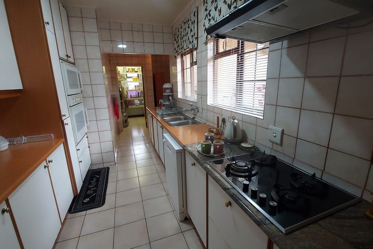 A functional kitchen featuring built-in cabinetry, a gas hob with extractor fan, built-in oven, and tiled finishes throughout.