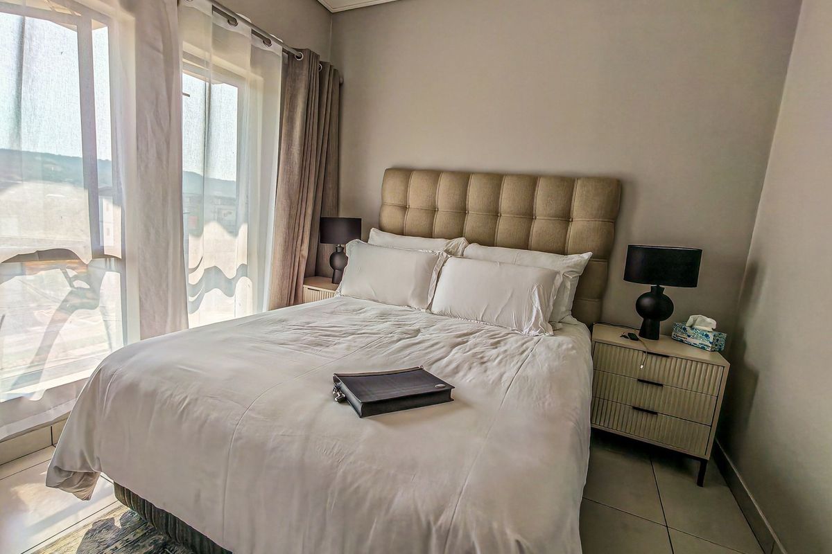 A well-maintained bedroom featuring tiled flooring and a large sliding glass door that provides ample natural light and access to the balcony.