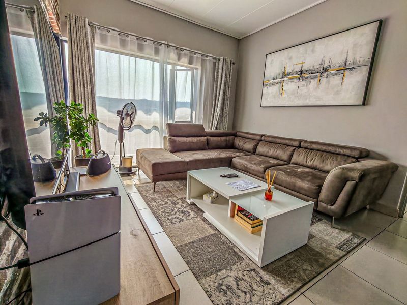 A comfortable living room featuring large sliding glass doors that provide natural light and access to the exterior, complemented by neutral tiled flooring.