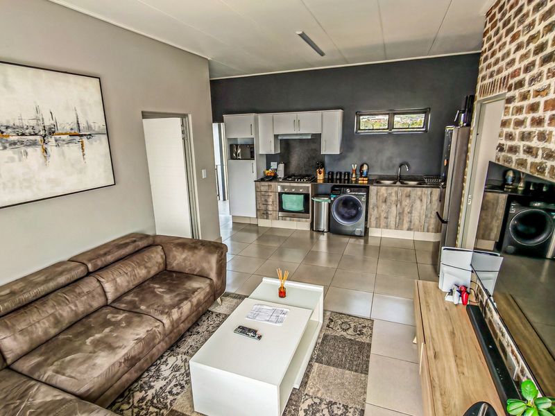 Open-plan living area featuring a modern kitchen with built-in cabinetry, gas hob, oven, and tiled flooring, seamlessly connected to the lounge space.