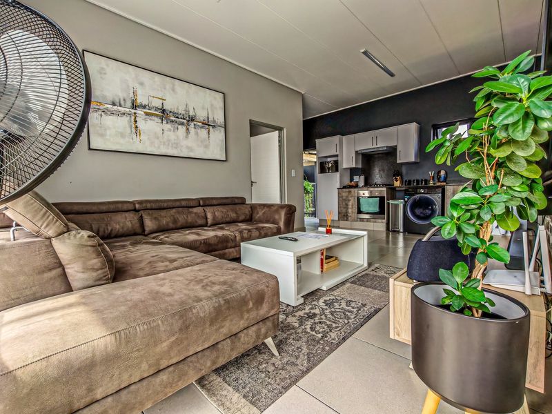 An open-plan living area featuring a modern kitchen with built-in appliances and tiled flooring, seamlessly connected to a comfortable lounge space.