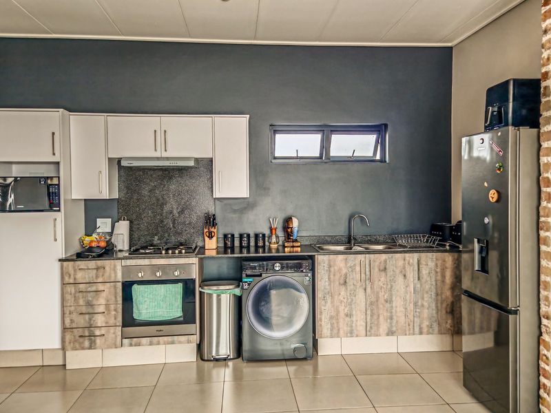Modern kitchen featuring built-in oven, gas hob, extractor fan, integrated microwave, and ample cabinetry with stone countertops and tiled flooring.