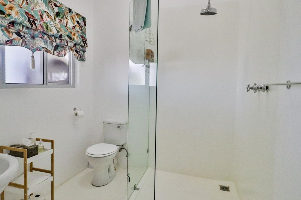 A clean, modern bathroom featuring a glass-enclosed shower, white sanitary ware, and a functional layout with neutral finishes.