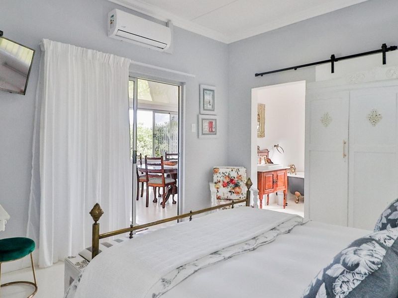 Spacious bedroom featuring a split-system air conditioner, sliding glass door access to the patio, and a convenient en-suite bathroom with a barn door entry.