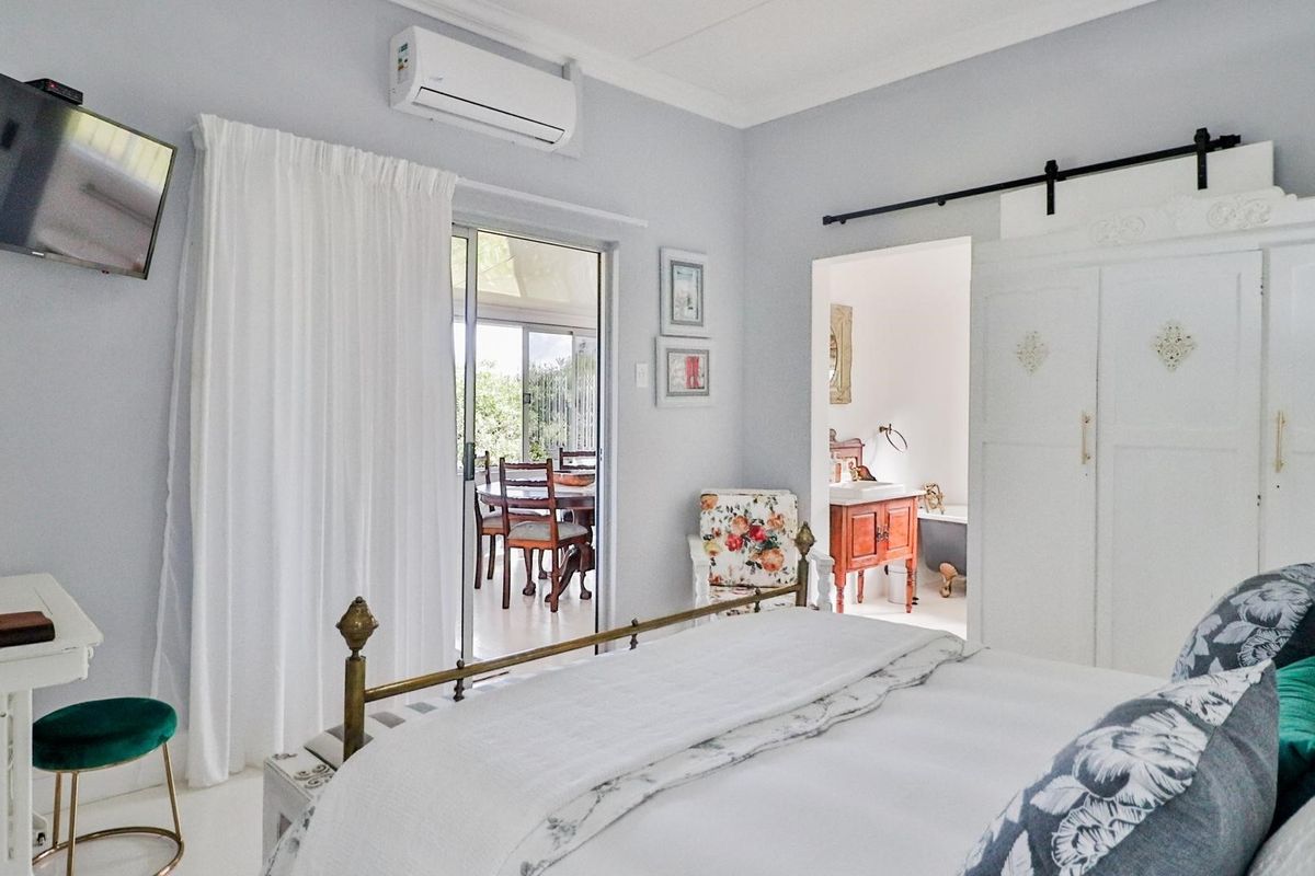 Spacious bedroom featuring a split-system air conditioner, sliding glass door access to the patio, and a convenient en-suite bathroom with a barn door entry.