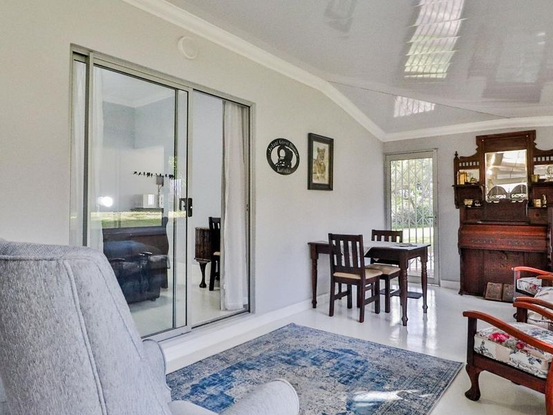 A bright, enclosed patio area featuring large sliding glass doors, glossy ceiling finishes, and tiled flooring, offering a comfortable transition space to the outdoors.