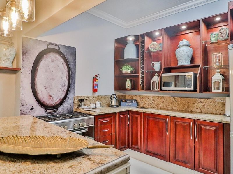 A well-appointed kitchen featuring rich wooden cabinetry, granite countertops, and a gas stove, complemented by integrated shelving and warm accent lighting.