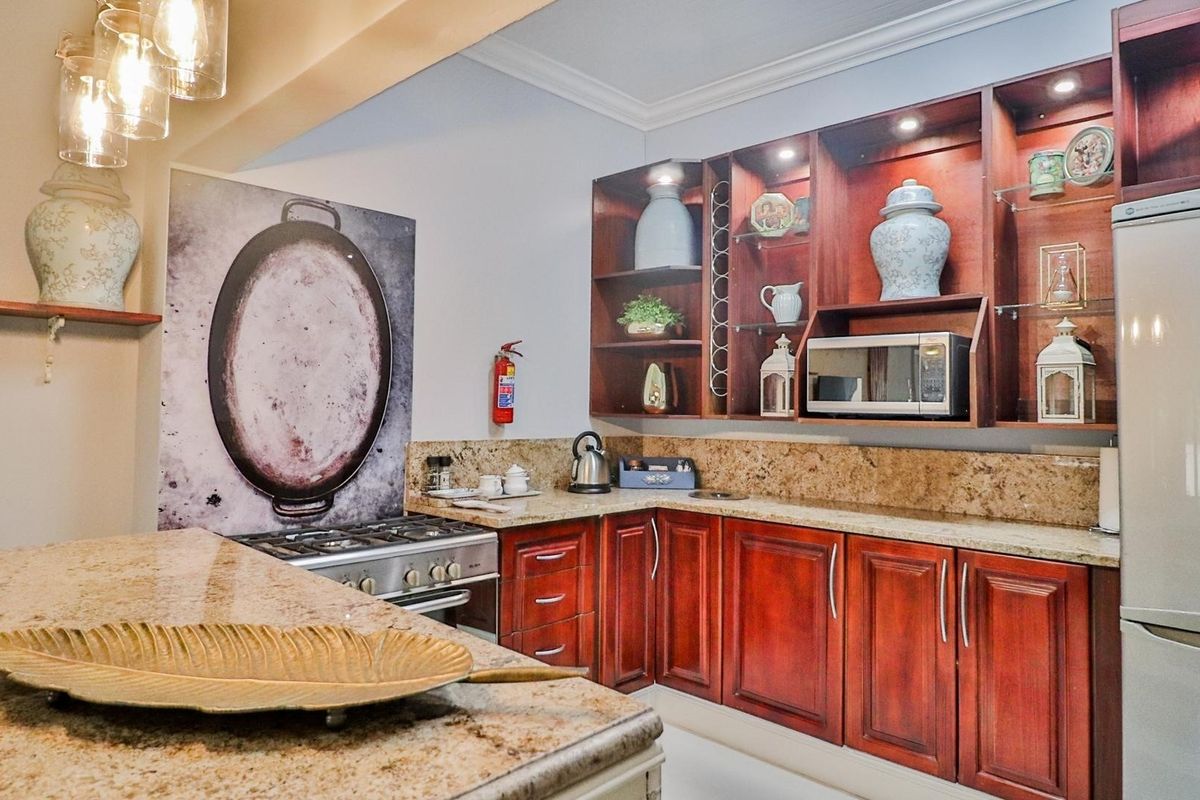 A well-appointed kitchen featuring rich wooden cabinetry, granite countertops, and a gas stove, complemented by integrated shelving and warm accent lighting.