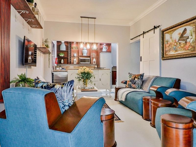 Open plan living area featuring a cozy lounge space flowing into a functional kitchenette with built-in cabinetry and stylish pendant lighting.