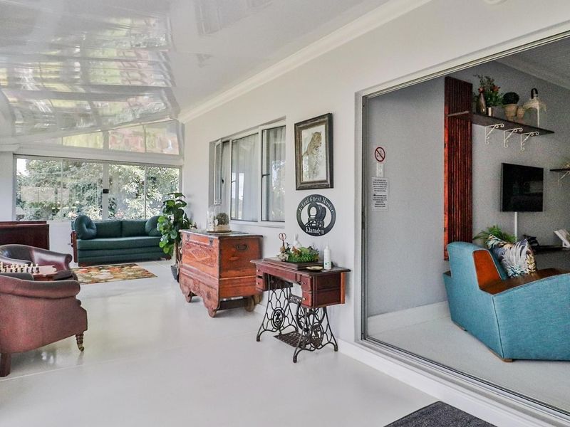 A bright, enclosed patio area featuring large sliding glass doors, a glossy ceiling, and expansive windows overlooking the garden.