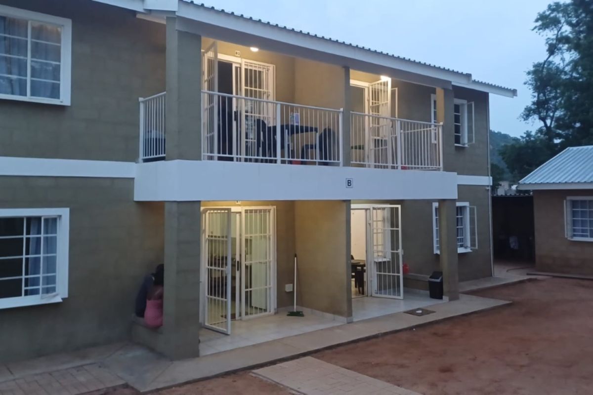 A two-story residential building featuring a ground-floor patio and an upper-level balcony with security gates and metal railings.