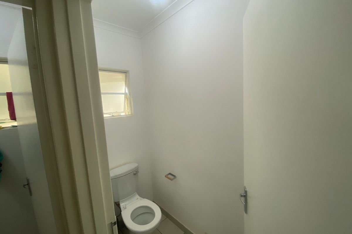 A compact, functional powder room featuring tiled flooring, a standard toilet, and a small casement window for natural light and ventilation.