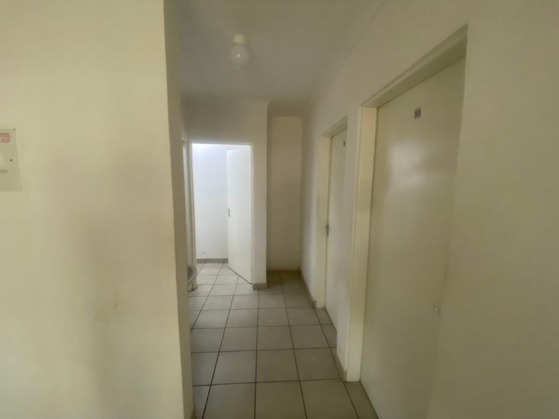 A functional hallway featuring tiled flooring and multiple internal doors, providing access to various rooms within the property.