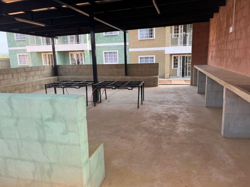A spacious covered outdoor patio area featuring built-in concrete counters and seating, offering a functional space for outdoor entertaining.