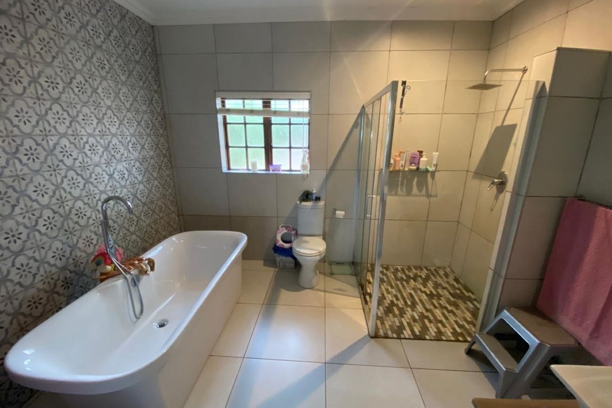 Modern bathroom featuring a freestanding bathtub, a spacious walk-in shower with glass enclosure, and stylish feature wall tiling.