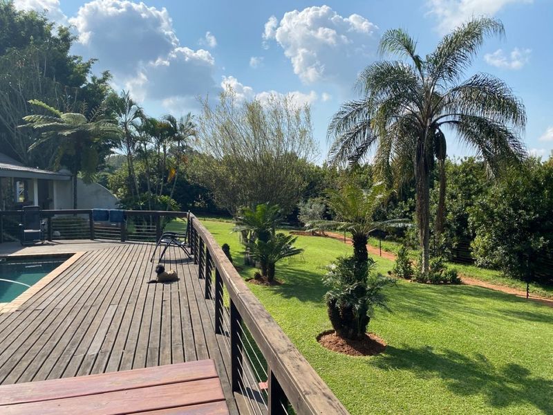Spacious timber deck overlooking a swimming pool and a well-maintained garden area on a small holding property.