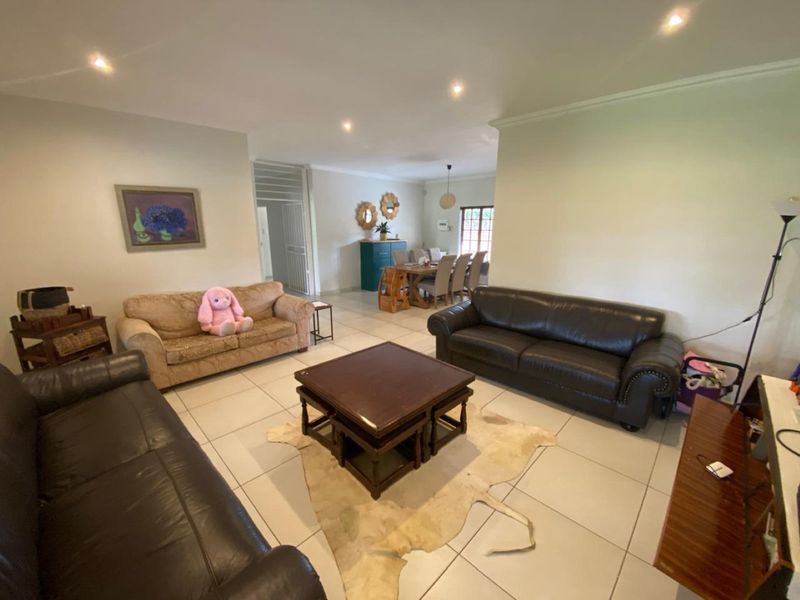 Spacious open-plan living and dining area featuring neutral tiled flooring, recessed downlighting, and classic cornicing throughout the connected living spaces.