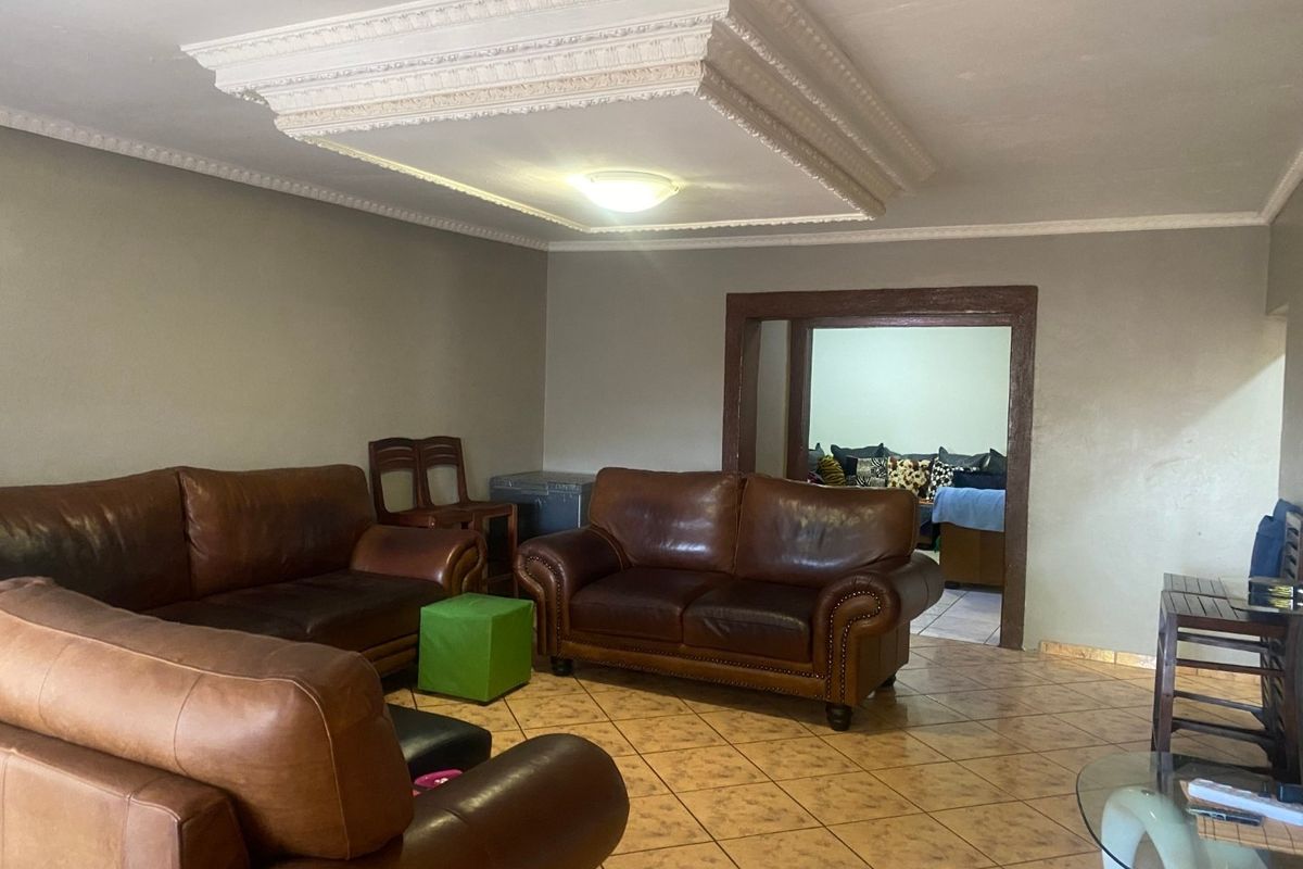 Spacious living room featuring a decorative coffered ceiling, ceramic tile flooring, and a wide doorway leading to an adjacent room.
