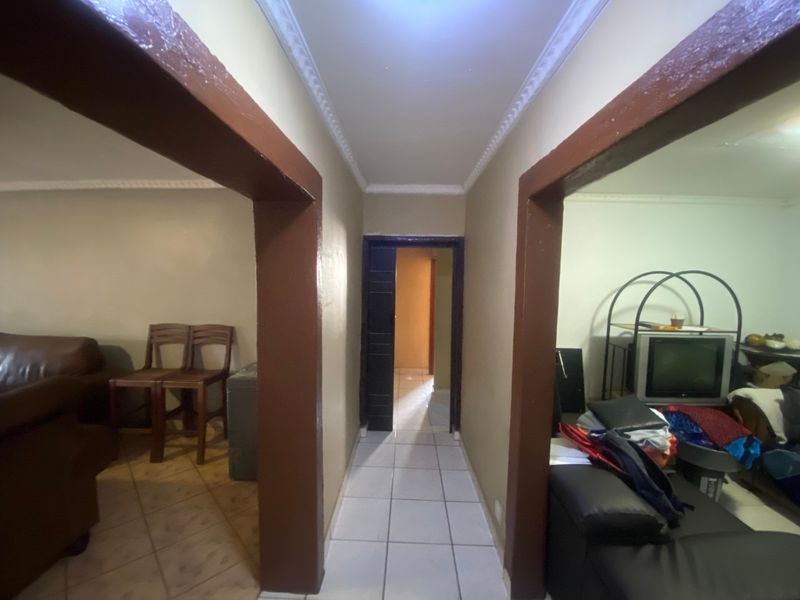 A central hallway featuring tiled flooring and decorative ceiling cornicing, connecting multiple living areas within the home.
