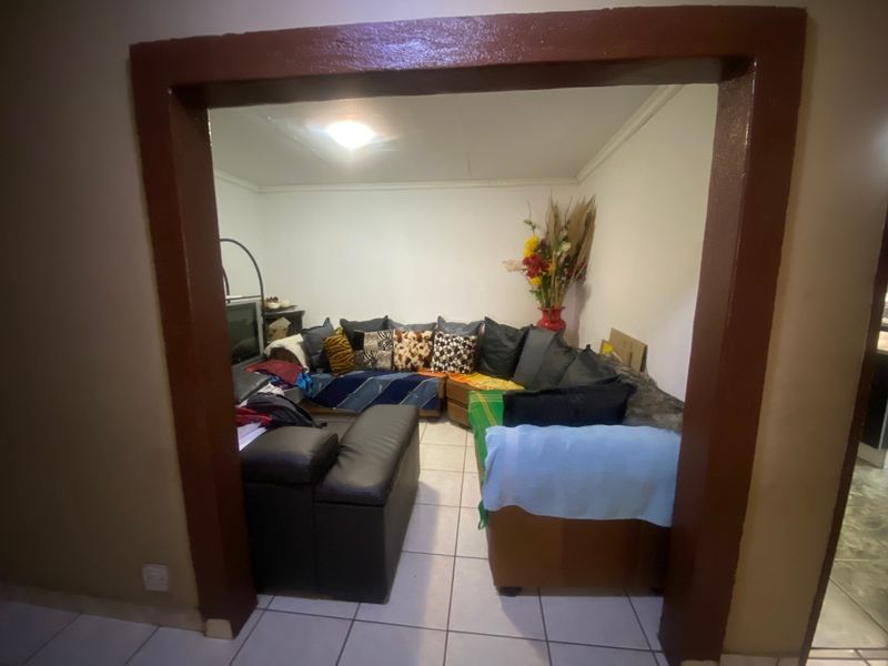A living room space featuring tiled flooring and a distinct archway entrance, requiring cosmetic updates to improve the overall aesthetic.