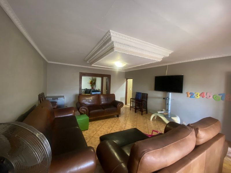A living room featuring ceramic floor tiles and a decorative ceiling molding with cove lighting.