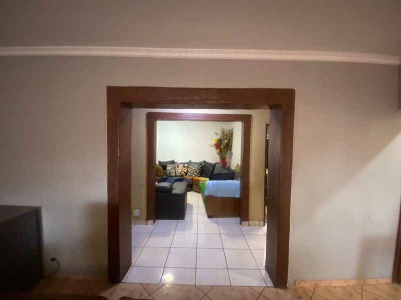 A view through a doorway into a living area featuring ceramic tiled flooring and decorative ceiling cornicing.