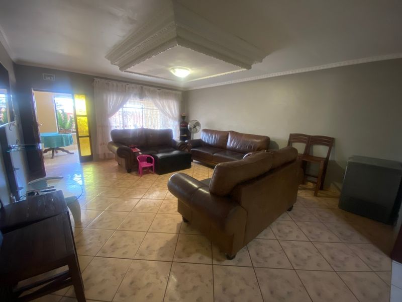 Spacious living room featuring tiled flooring, a decorative recessed ceiling feature with cornice, and direct access to an outdoor area through a sliding door.