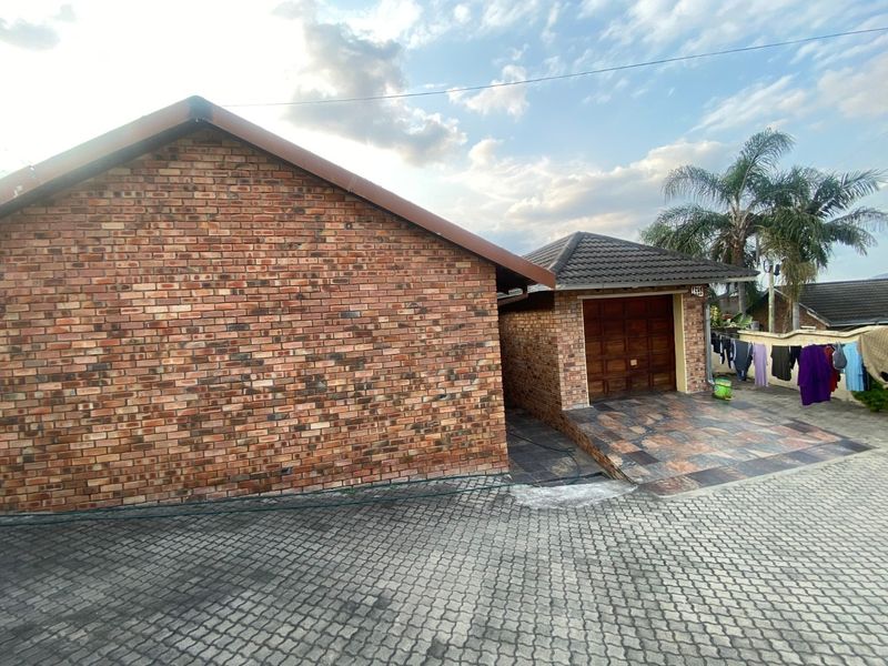 Front view of the property featuring a face brick exterior, tiled roof, and a paved driveway leading to a garage.