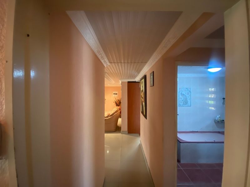 A hallway featuring tiled flooring and a panelled ceiling, providing access to adjacent rooms including a bathroom.