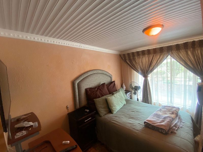 A bedroom featuring a panelled ceiling with decorative molding and a flush mount light fixture.