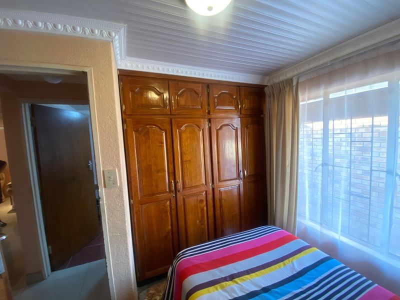 A bedroom featuring built-in wooden cupboards, decorative ceiling cornices, and a tongue and groove ceiling finish.