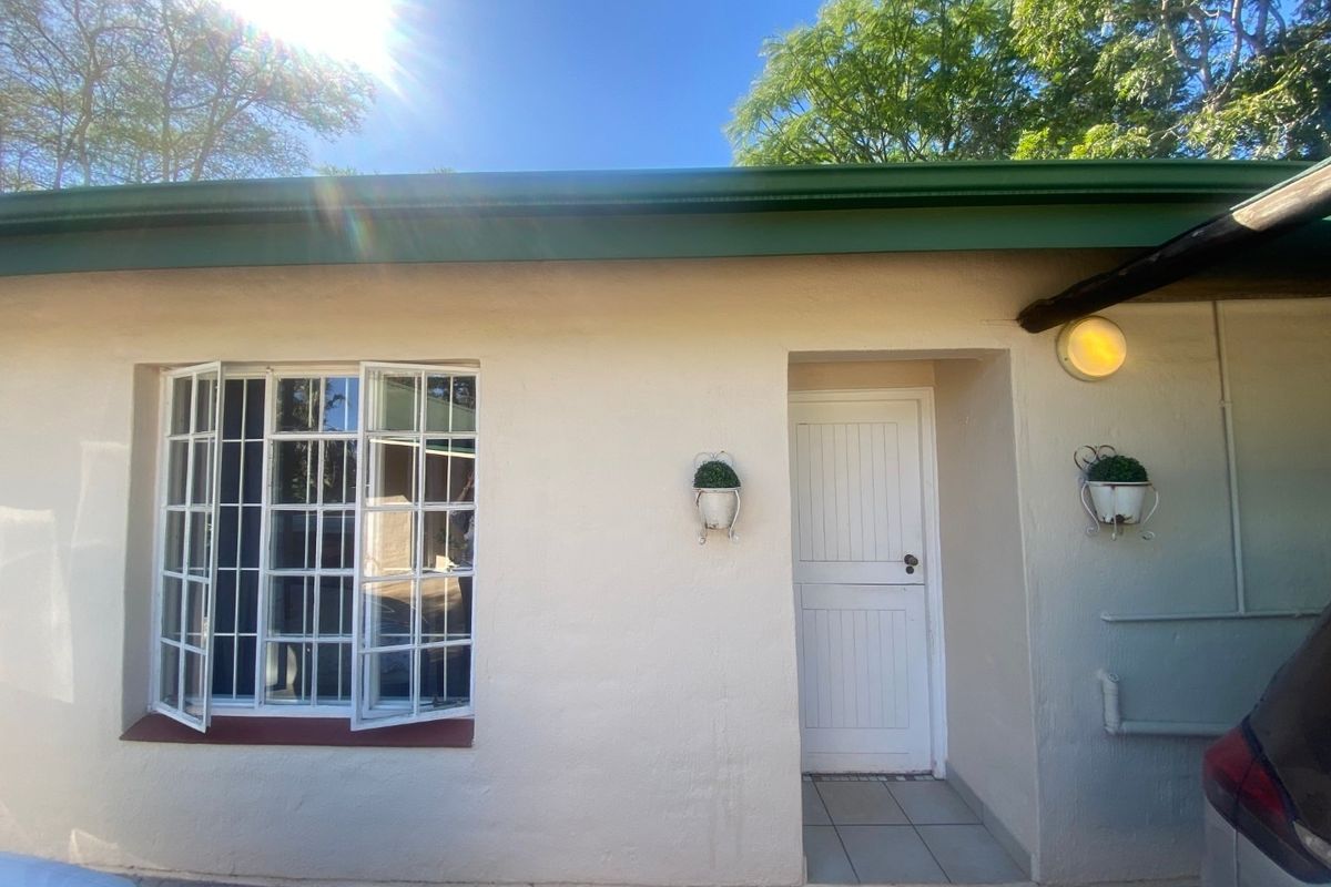Front exterior view of the property featuring a white facade, casement windows with security bars, and a tiled entrance area.