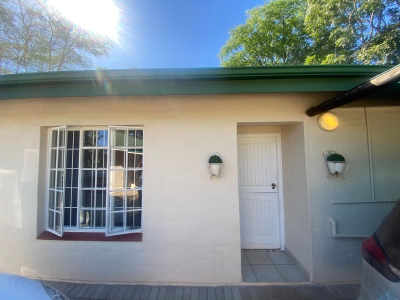 Front exterior view of the property featuring a white facade, casement windows with security bars, and a tiled entrance area.